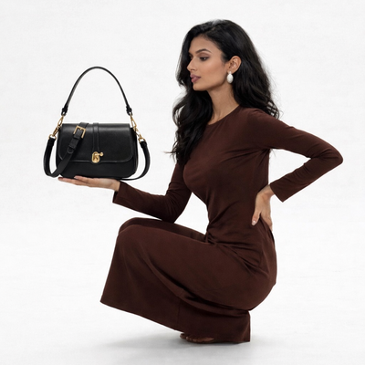 Woman in a brown dress holding a black handbag on a white background